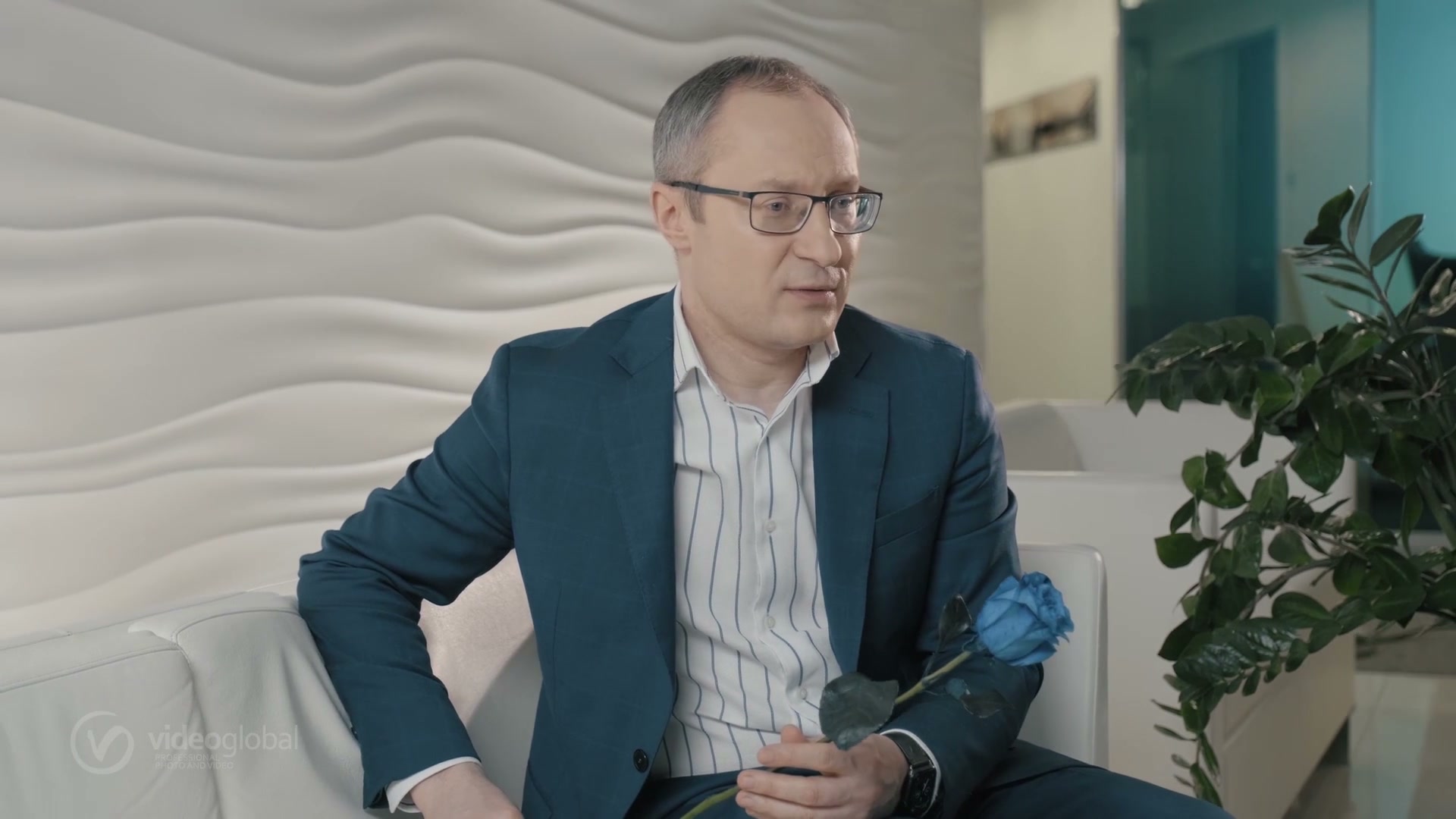 кейс ВТБ · спикер в очках на диване с синей розой между дублями